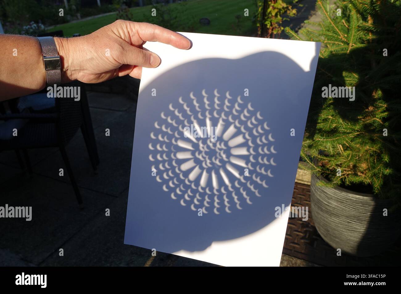 Partial solar eclipse viewed through a colander Stock Photo