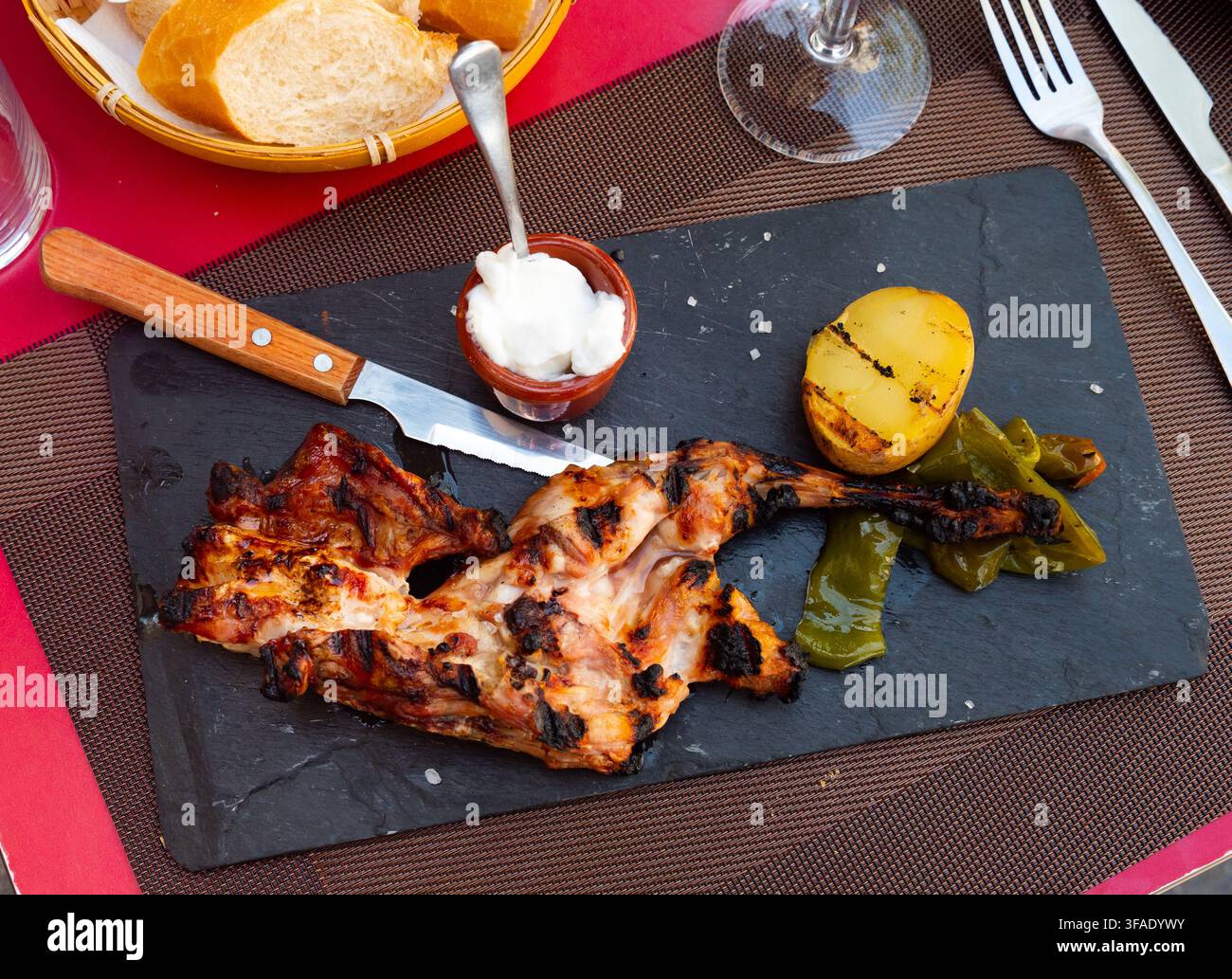 Roast rabbit served with potatoes and braised peppers Stock Photo
