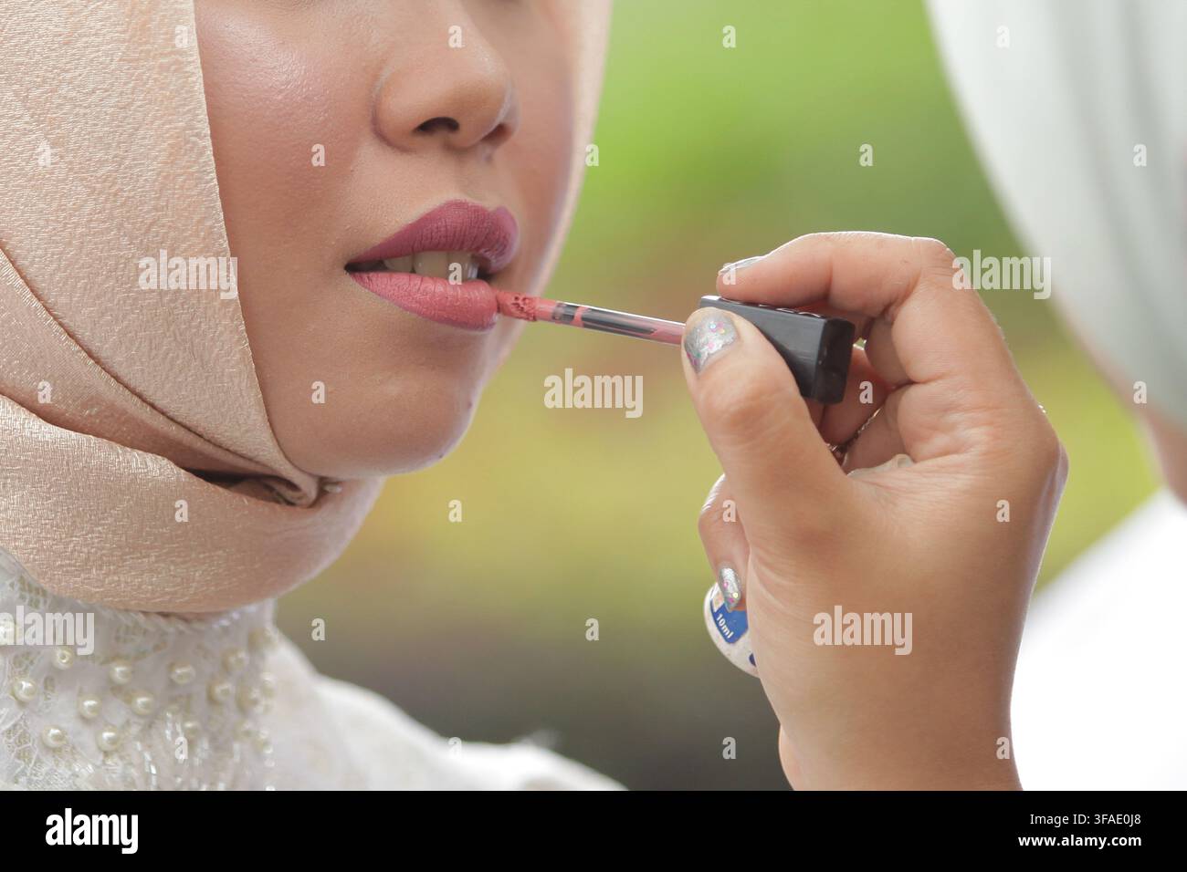 East Java,11/02/2019  Makeup Artist Applying Lipstick to Client's Lips Stock Photo