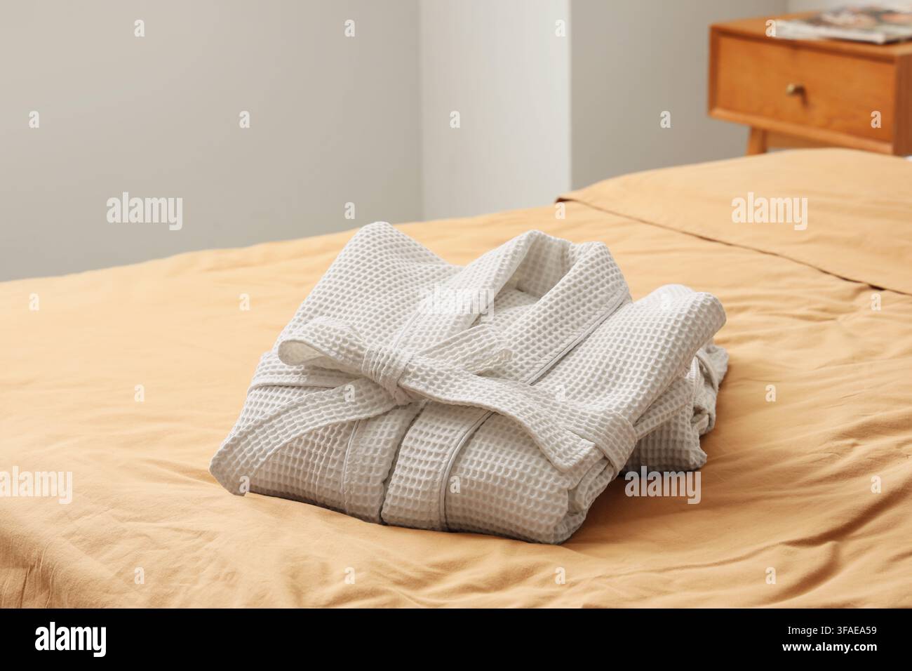 Folded waffle bathrobes on bed in room Stock Photo