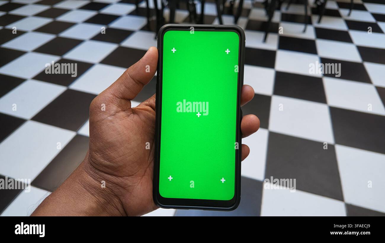 Hand holding a smartphone with a green screen display Stock Photo