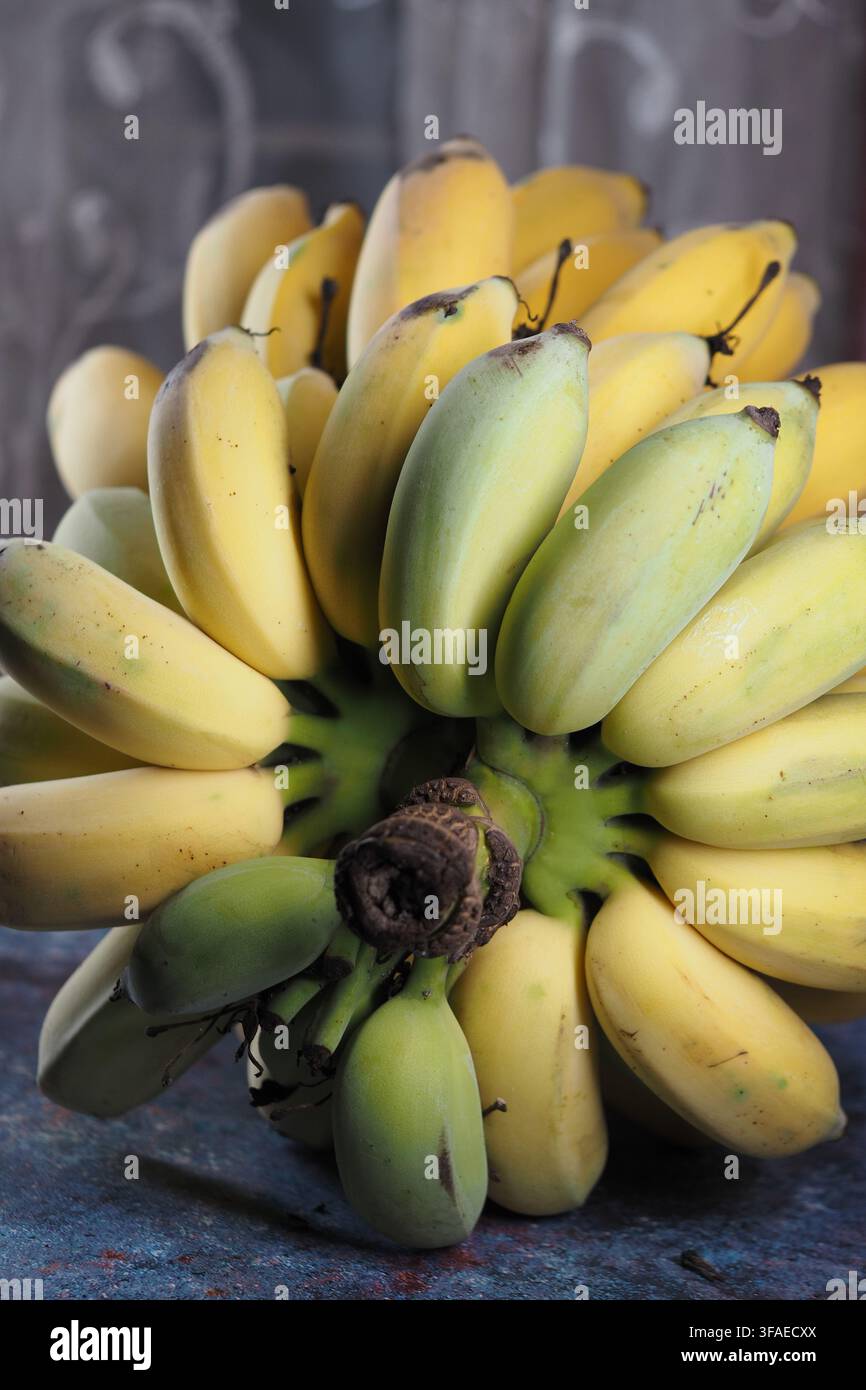 Bananas arranged in a bunch on a blue table surface Stock Photo