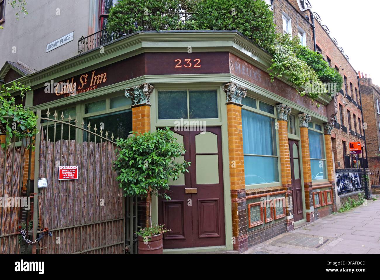 Former public house frontage at 232 Cable Street, Shadwell, with surviving Meux's stout and ales tiling and old West Street corner details. Stock Photo