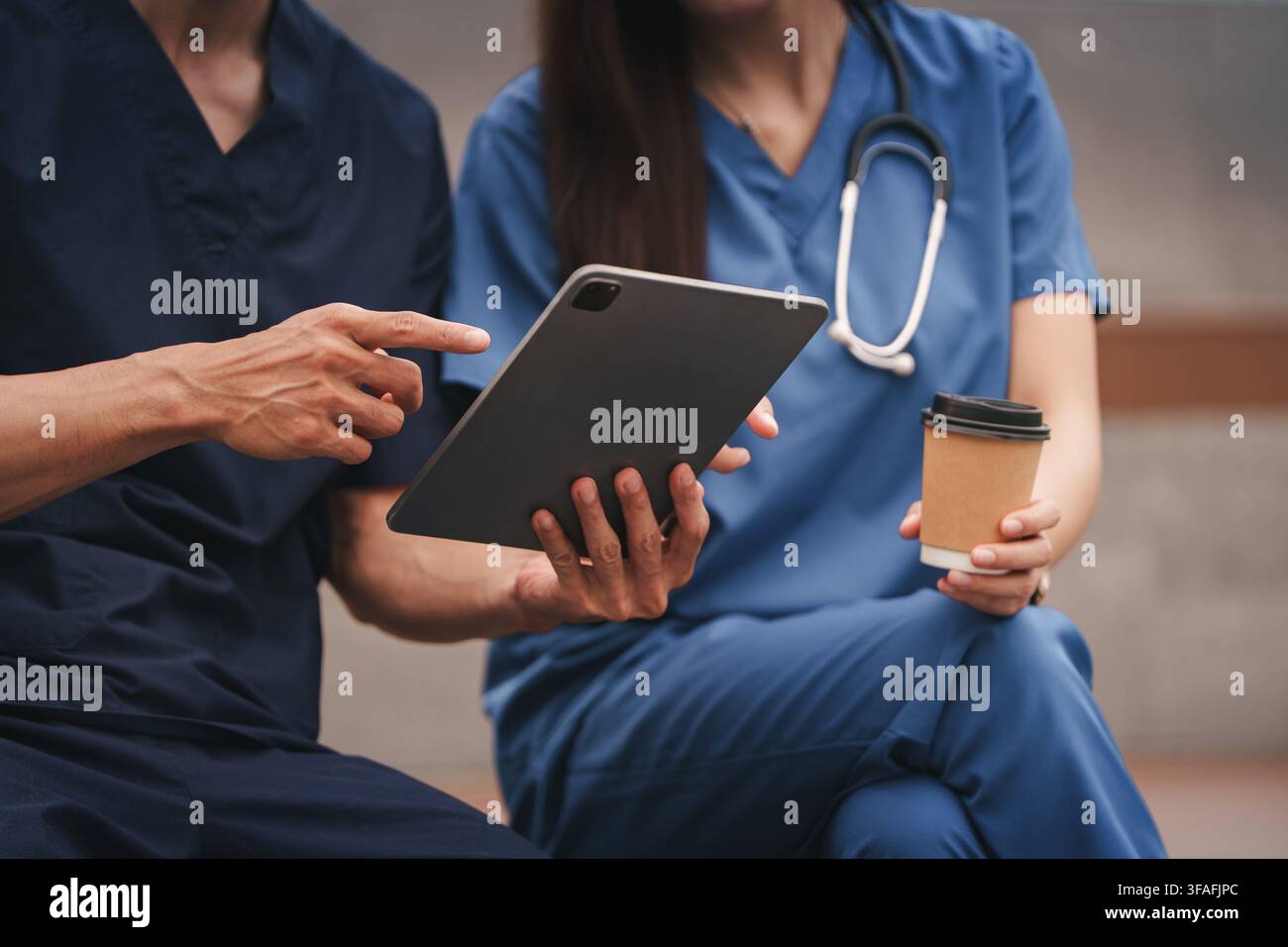 Medical team using digital tablet during coffee break time outdoors Stock Photo