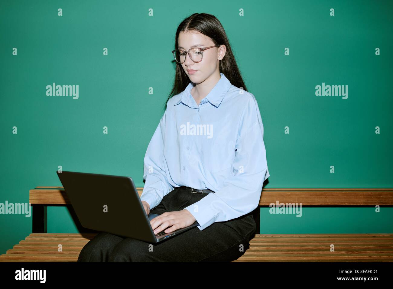 Female Student Using Laptop on Campus Bench for Online Learning Stock Photo