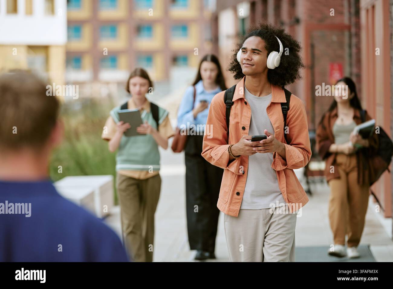 Diverse Students Walking on Campus and Using Smartphones Stock Photo