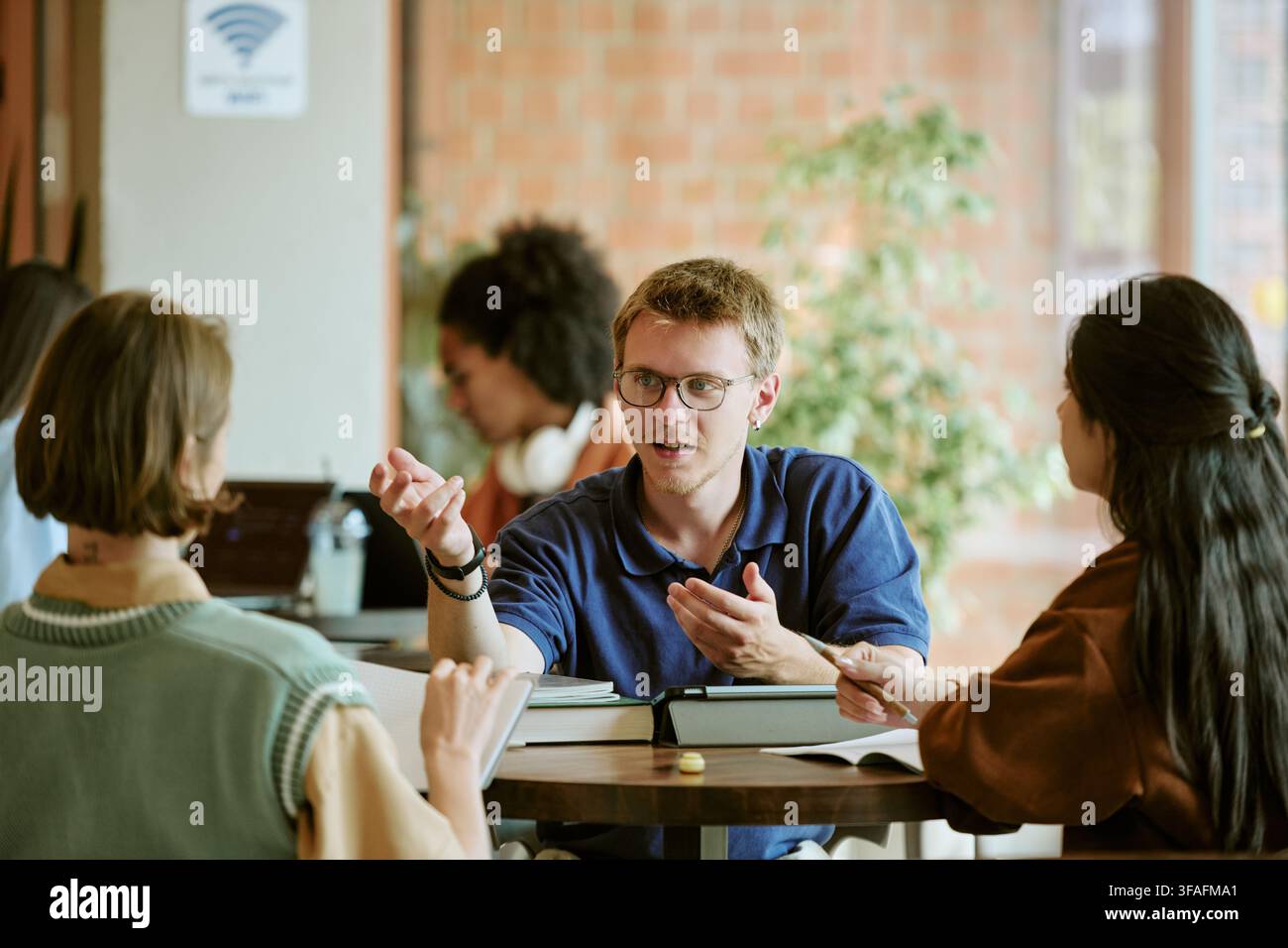 Diverse Students Studying and Discussing Project in Campus Cafe Stock Photo