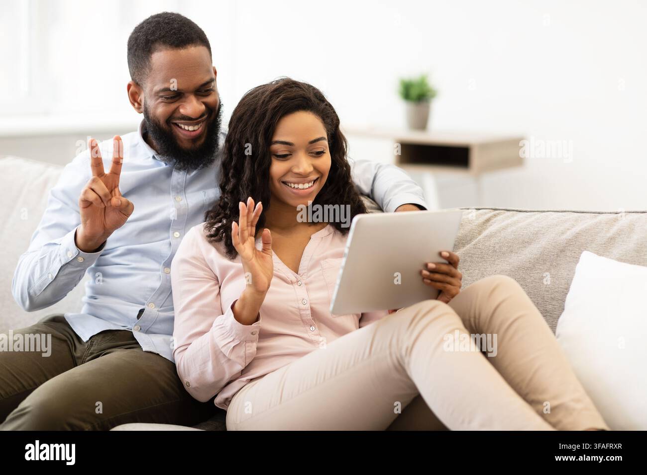 Black couple having videocall using tablet waving hands Stock Photo