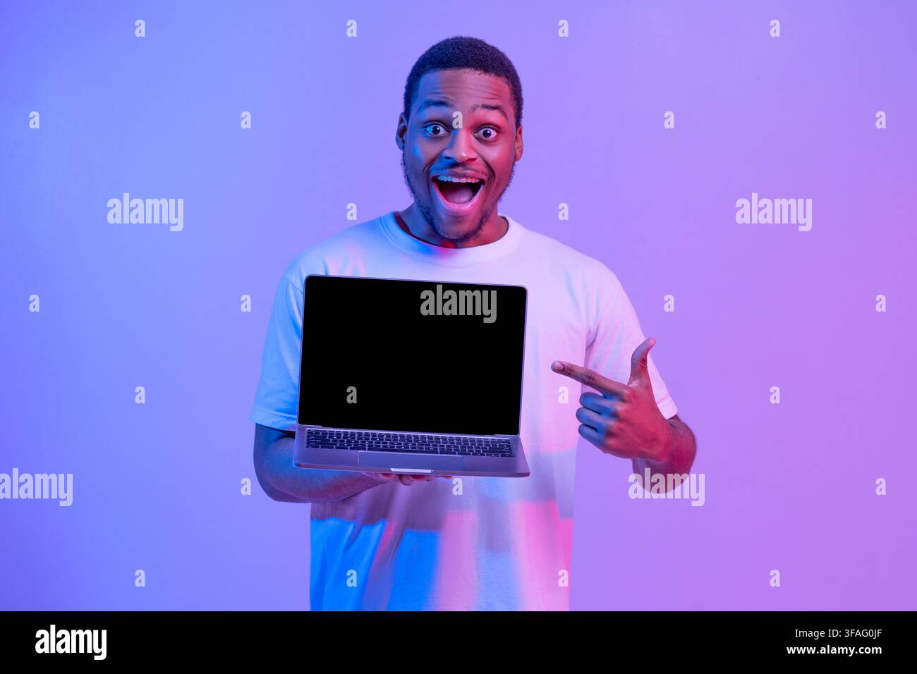 Check This. Overjoyed Black Guy Pointing At Laptop Computer With Blank Screen Stock Photo