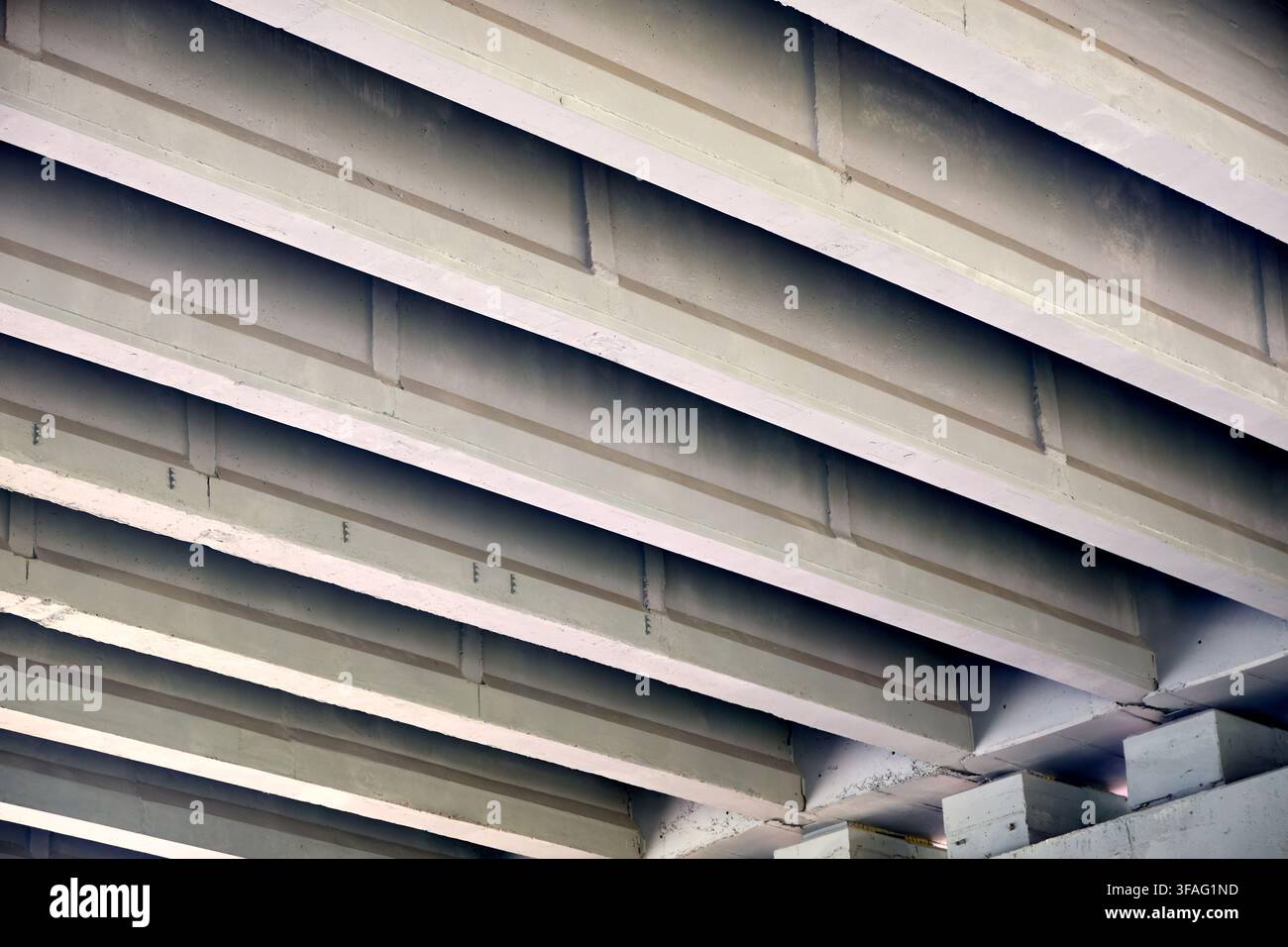 Concrete bridge underside featuring repeating diagonal beams, solid architectural structures, industrial infrastructure support, grey cement perspecti Stock Photo