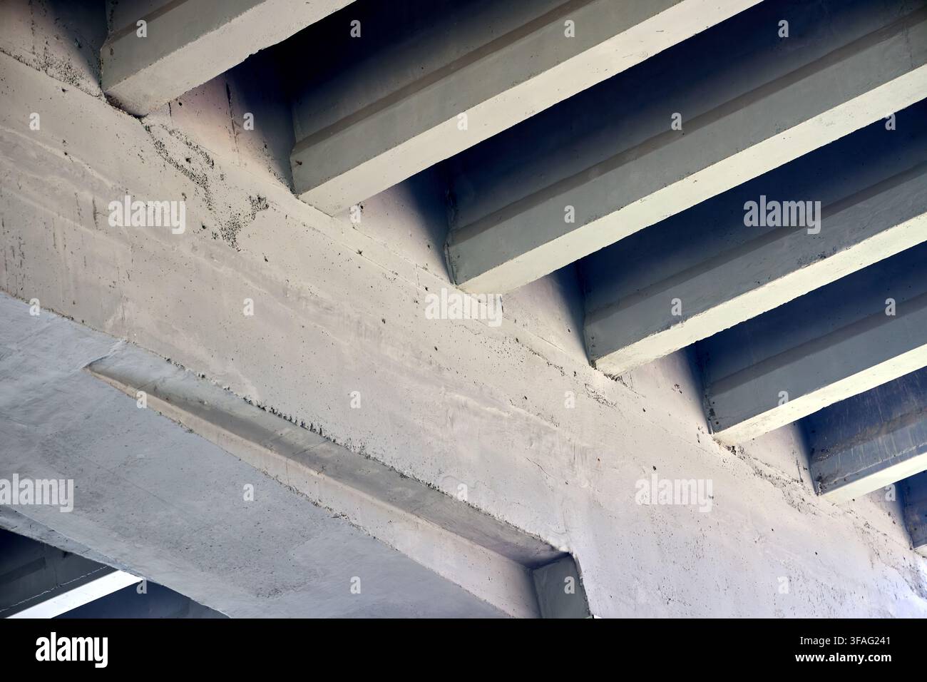 Concrete bridge underside featuring repeating diagonal beams, solid architectural structures, industrial infrastructure support, grey cement perspecti Stock Photo