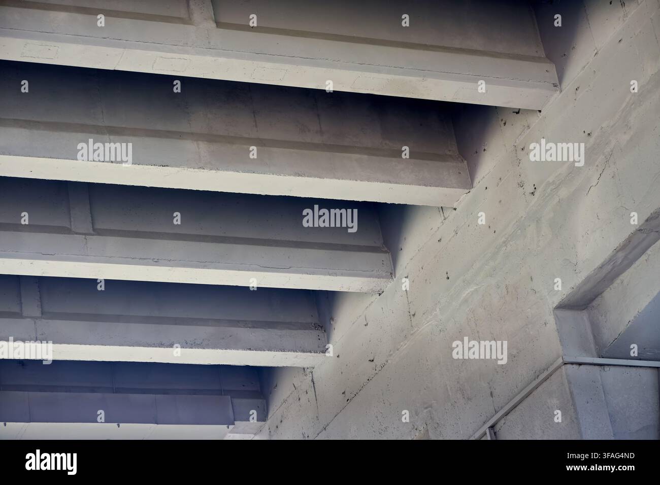 Concrete bridge underside featuring repeating diagonal beams, solid architectural structures, industrial infrastructure support, grey cement perspecti Stock Photo