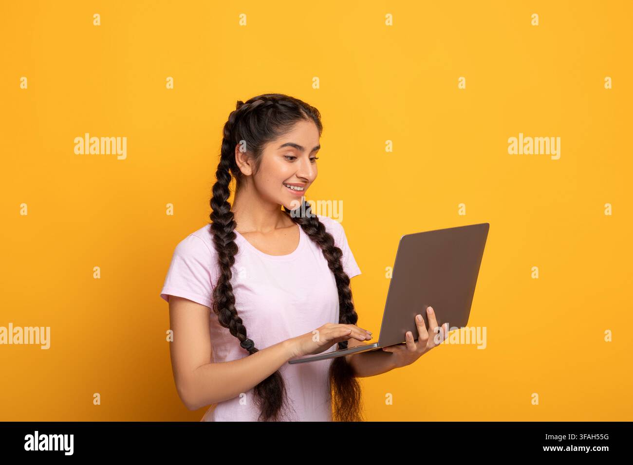 Smiling young indian lady holding and using laptop Stock Photo