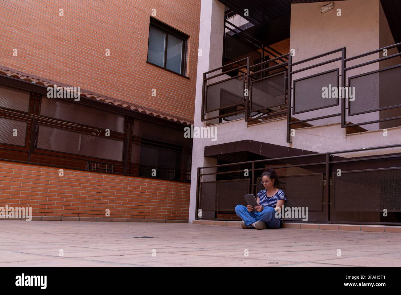 Female Reader Accessing Digital Content on Tablet in Urban Residential Setting Stock Photo