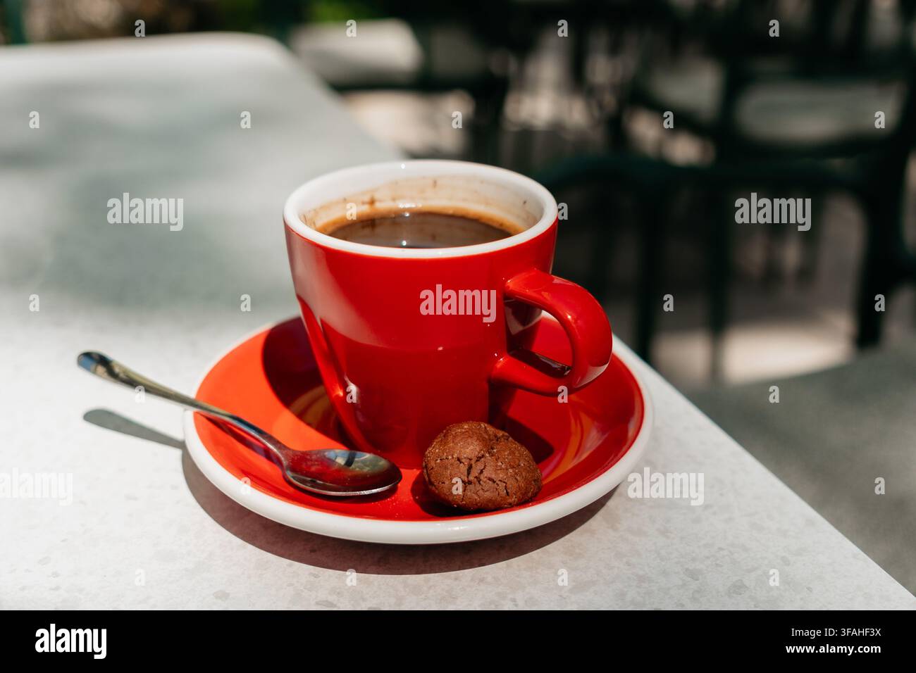 Fresh americano served in a red ceramic cup with cookie on a bright table. Smooth flavor and premium coffee moment create a stylish cafe lifestyle Stock Photo