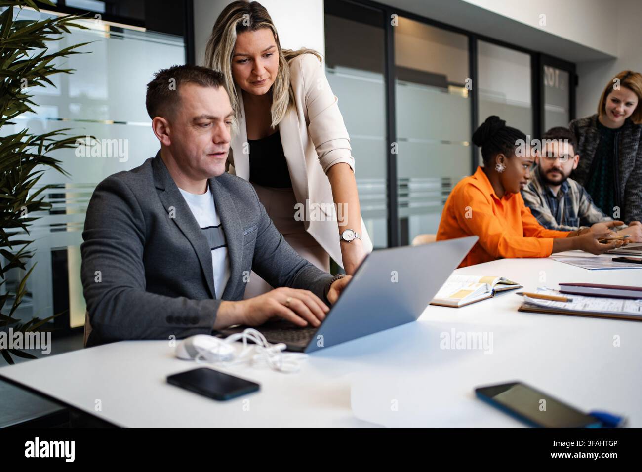 Diverse business team collaborating in modern office using laptop Stock Photo