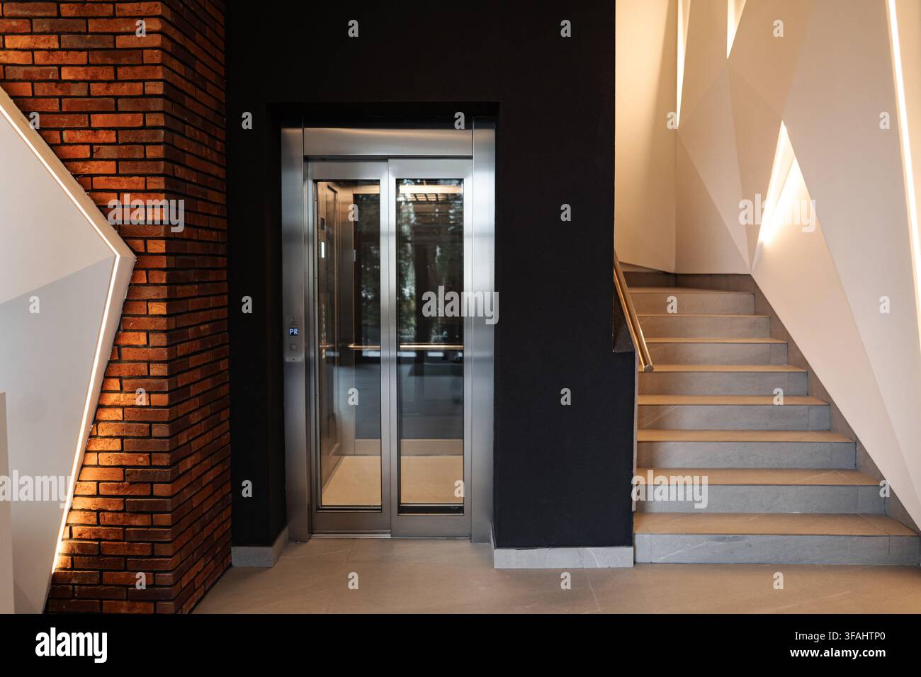 Modern interior featuring elevator and staircase with geometric lighting Stock Photo