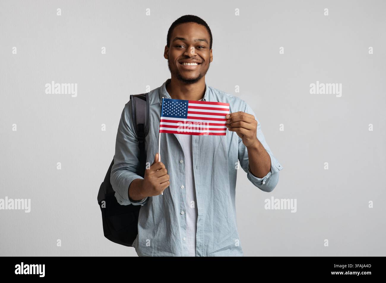 Positive black guy with backpack holding american flag Stock Photo