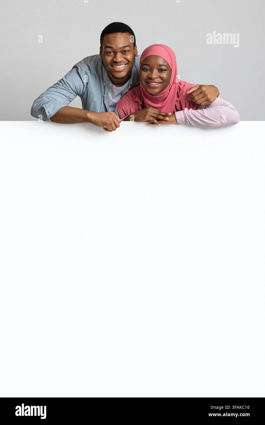 Cute african american couple leaning on white empty board Stock Photo