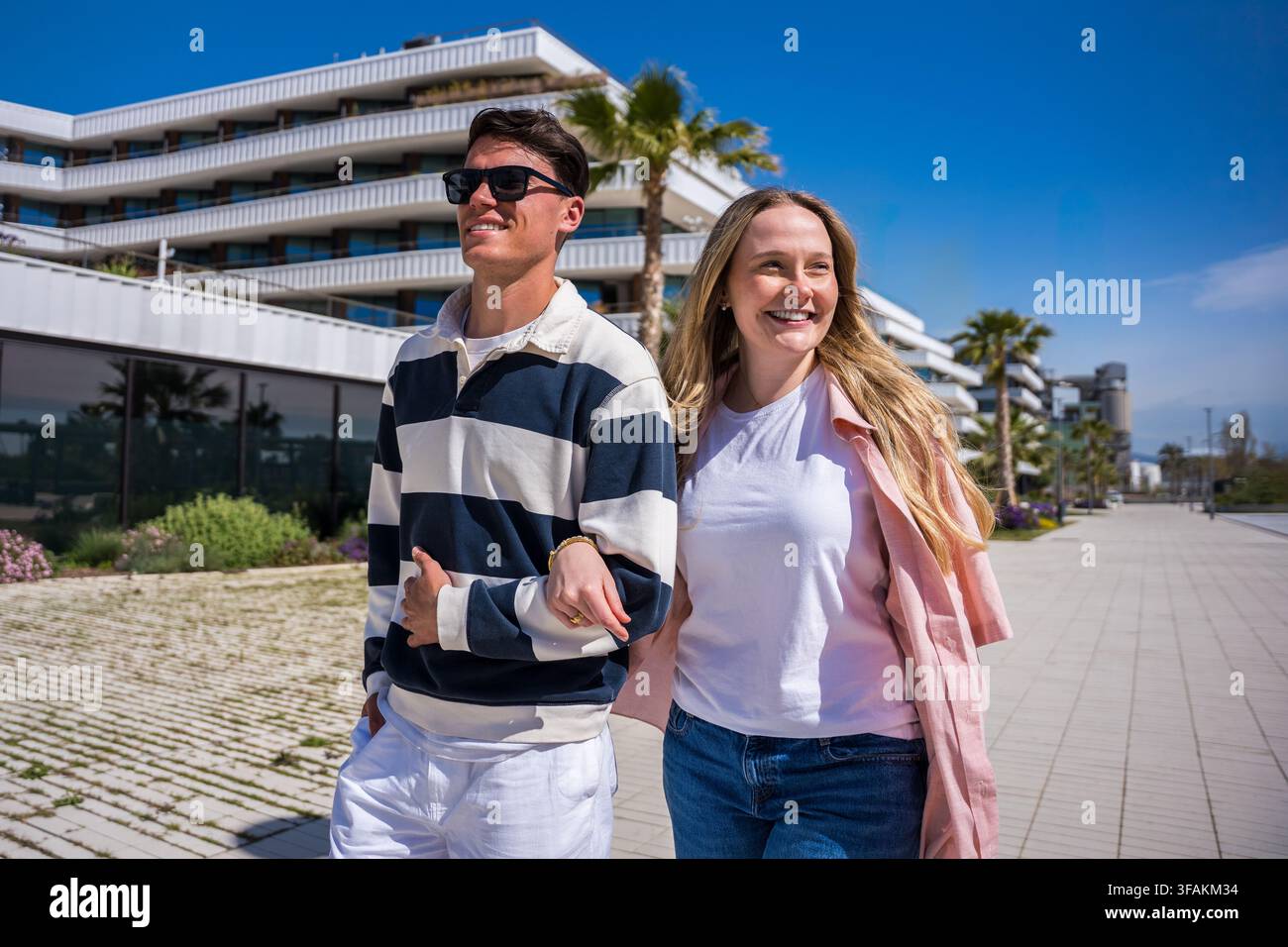 Young couple walking arm in arm and smiling in modern city Stock Photo