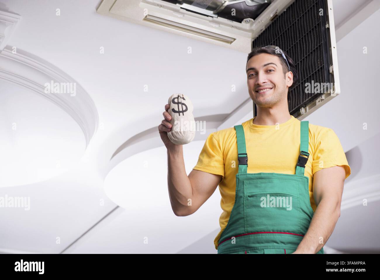 Young mechanic repairs ceiling air conditioner Stock Photo