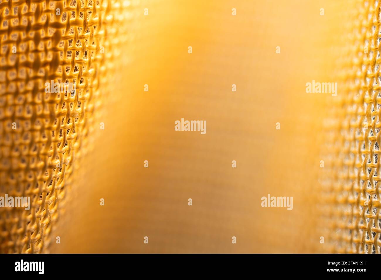 Soft golden abstract background framed by blurred metallic mesh edges with warm glow and central copy space for design Stock Photo
