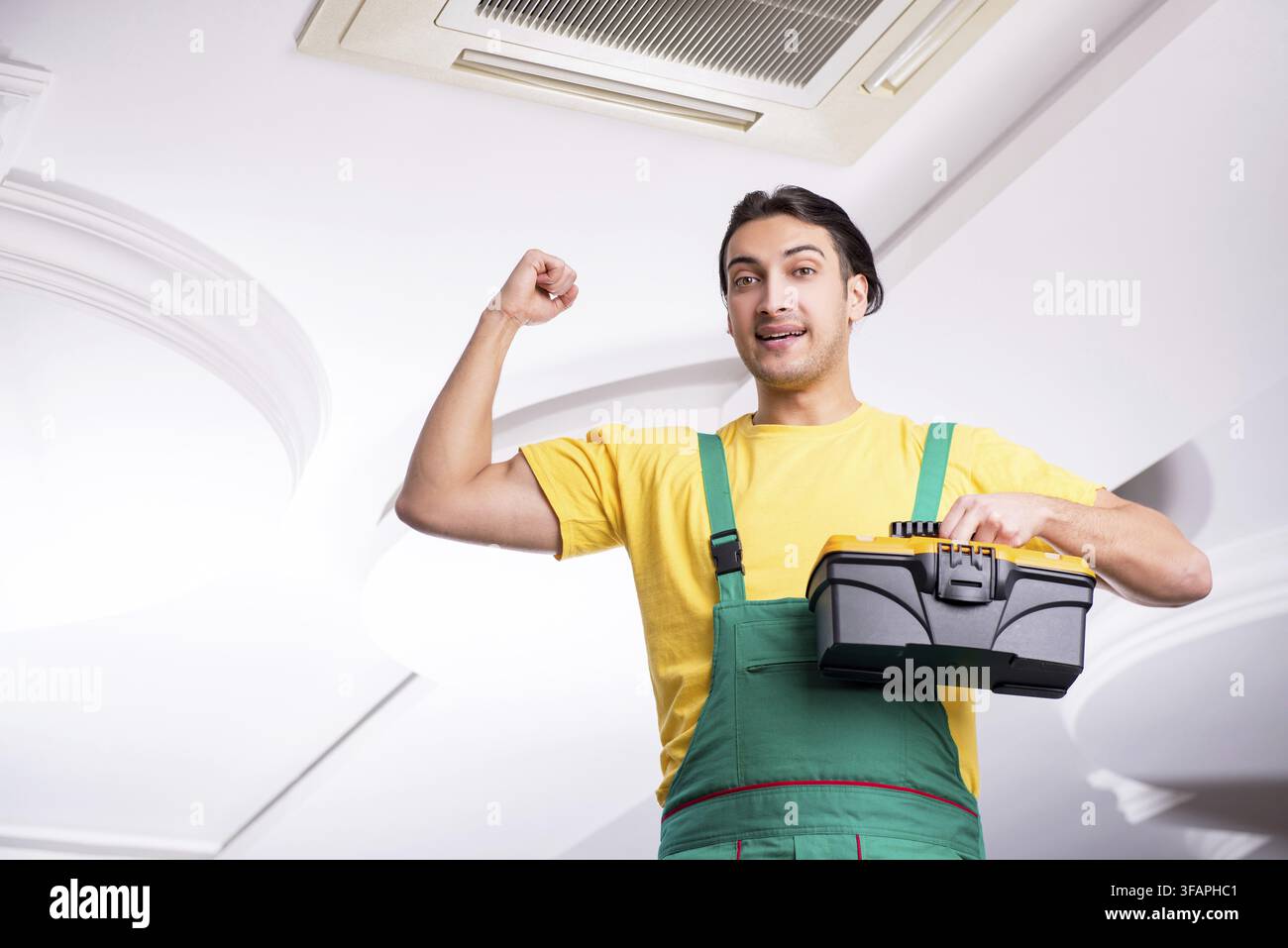 Young mechanic repairs ceiling air conditioner Stock Photo