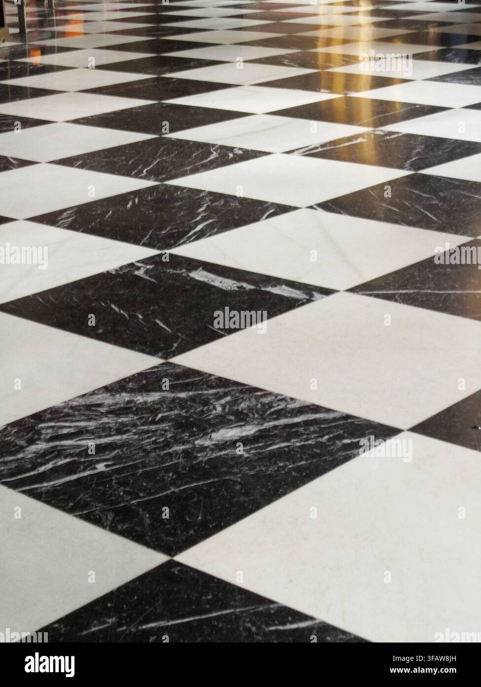 Marble floor tiles creating a diagonal checkerboard pattern with reflections Stock Photo