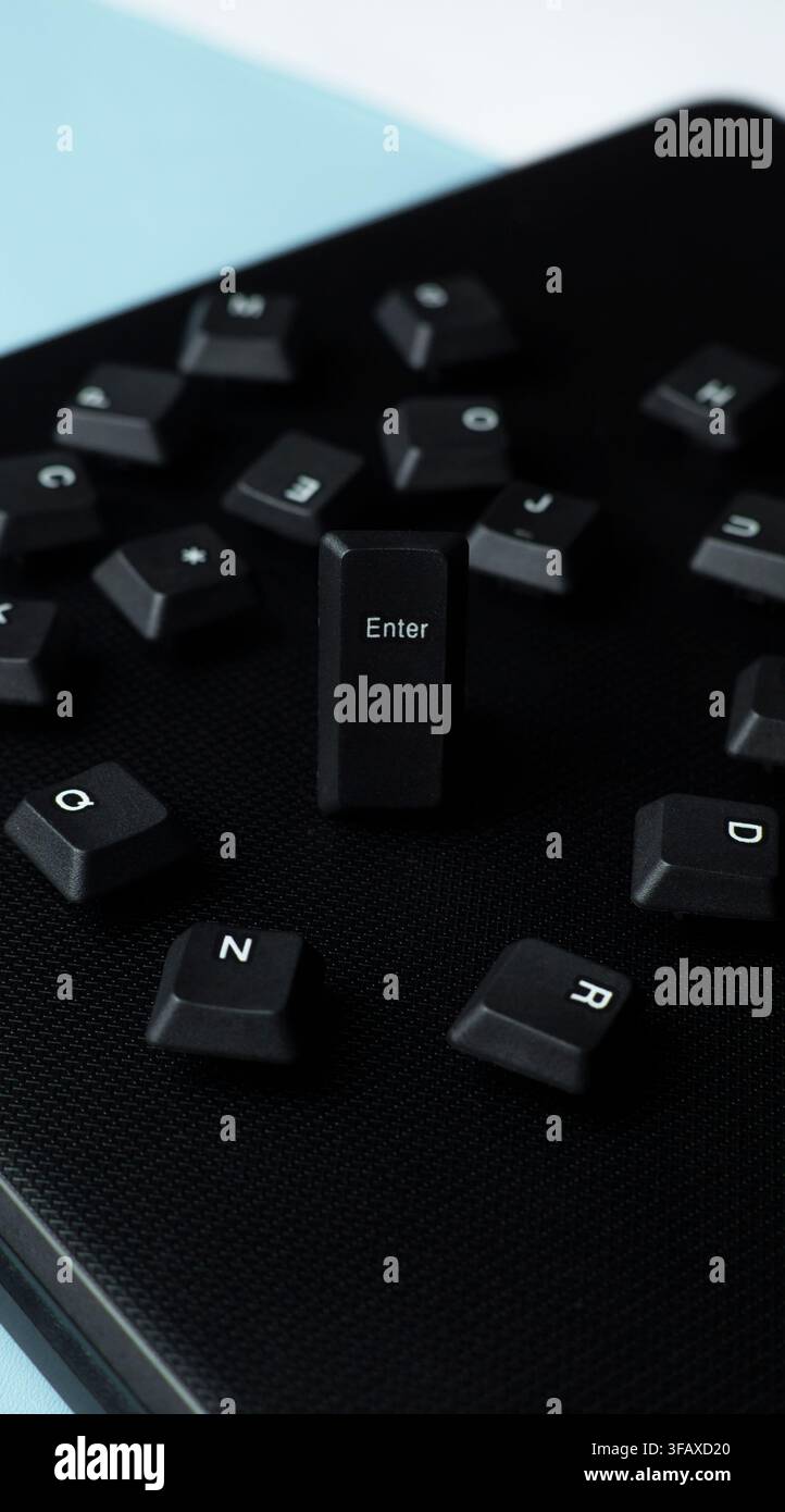 Scattered black keyboard keys with a focused Enter key on a dark laptop surface, representing input, access, submit, command, and digital action. Stock Photo