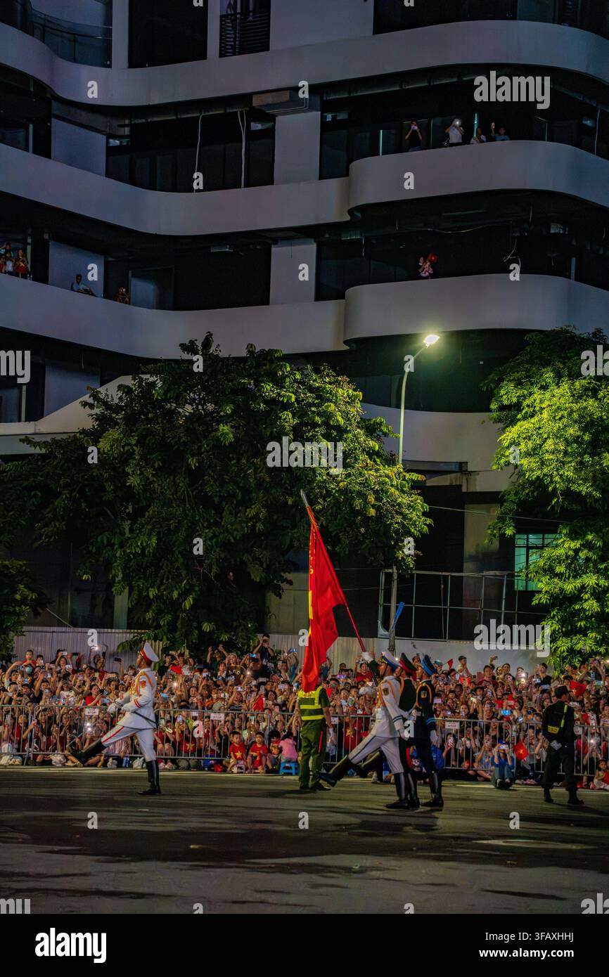 Ceremonial guards marching with flag past crowd, Van Cao, Hanoi night Stock Photo