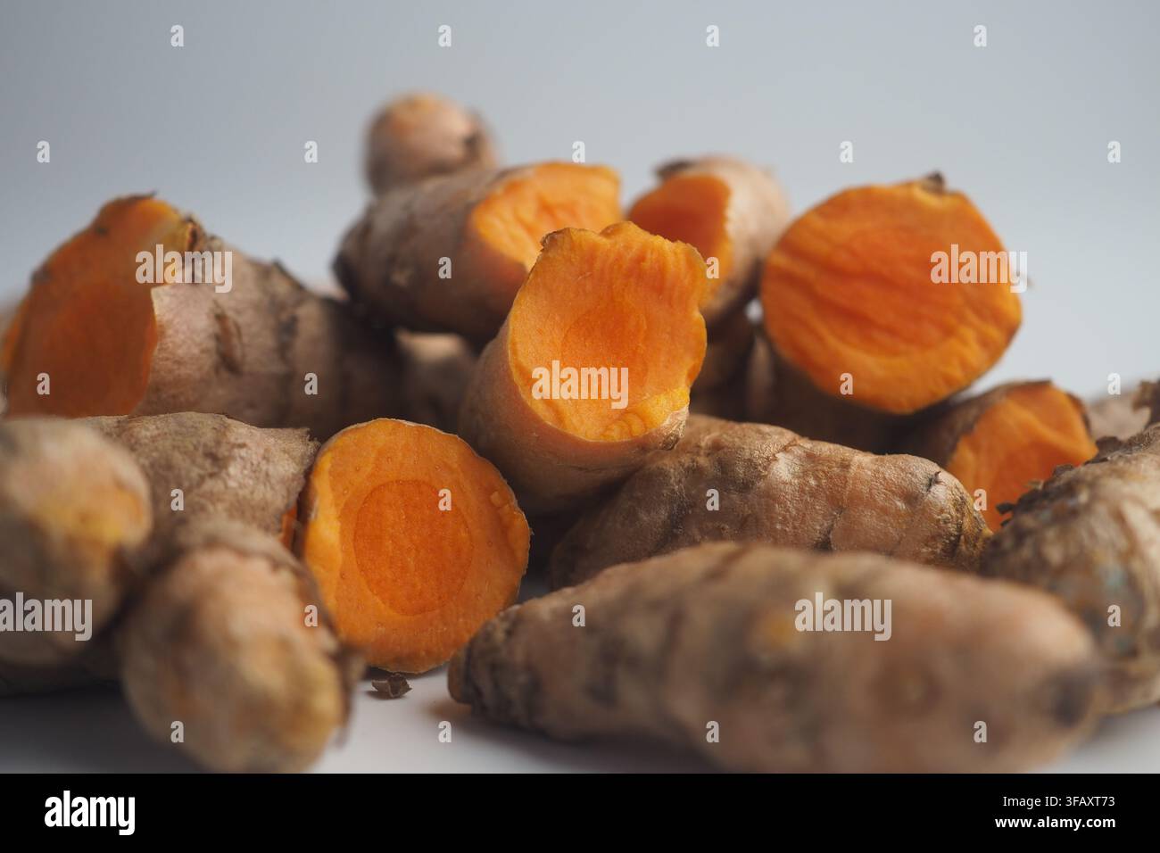 Fresh turmeric root displayed on a white surface Stock Photo