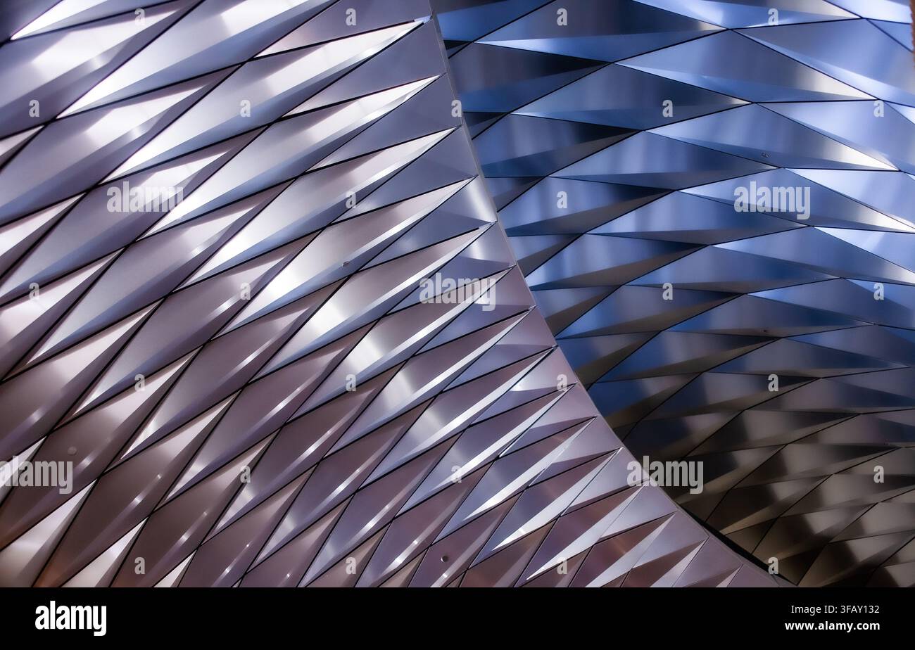 Abstract metallic interior ceiling with repeating folded panels in silver, gold and blue, modern architectural pattern. Stock Photo