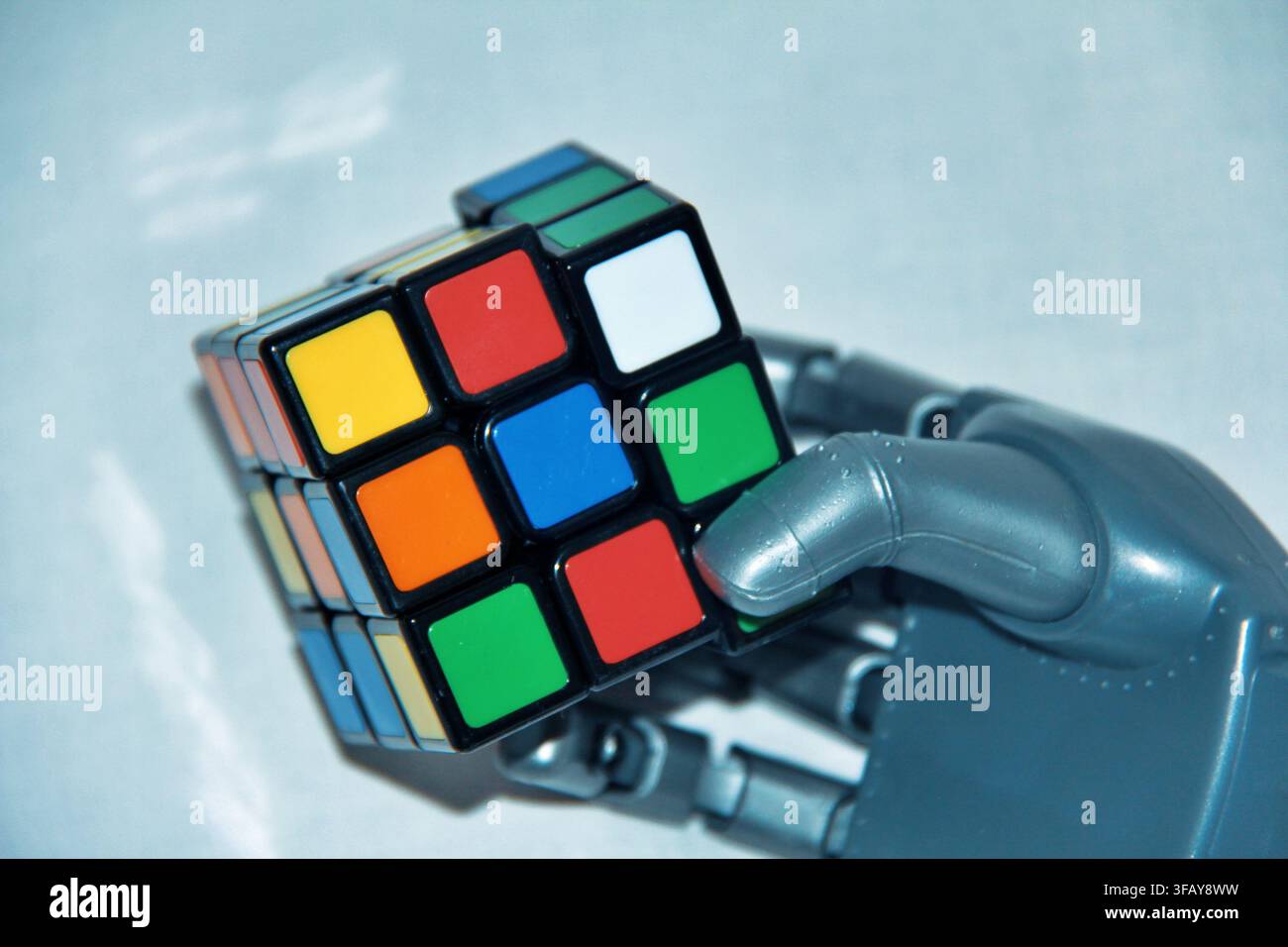 Robotic Hand Holding a Colorful Rubik's Cube, AI and Problem Solving Concept Stock Photo