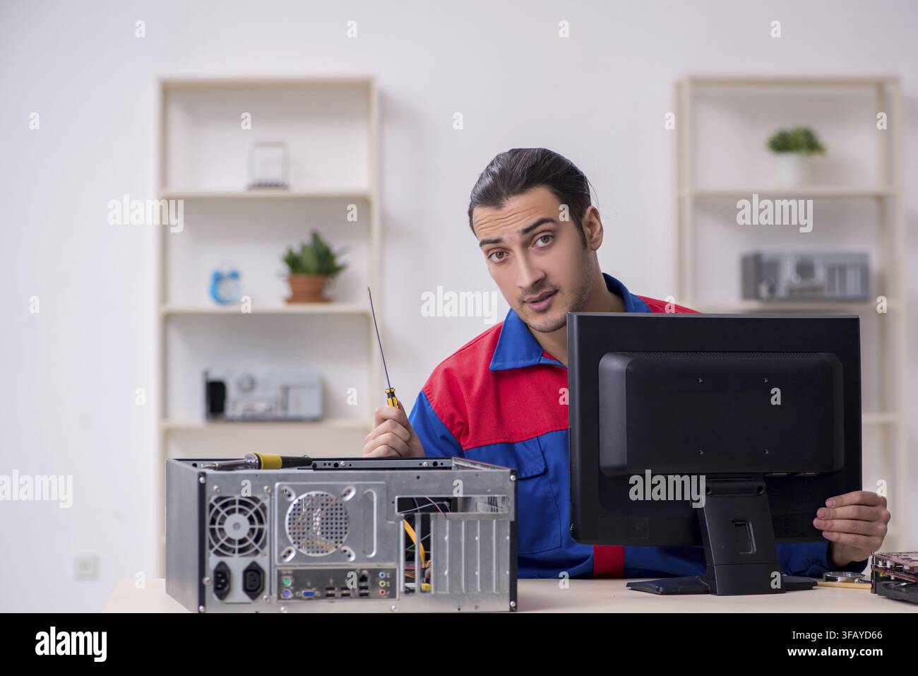 Young male mechanic repairs computer PC Stock Photo