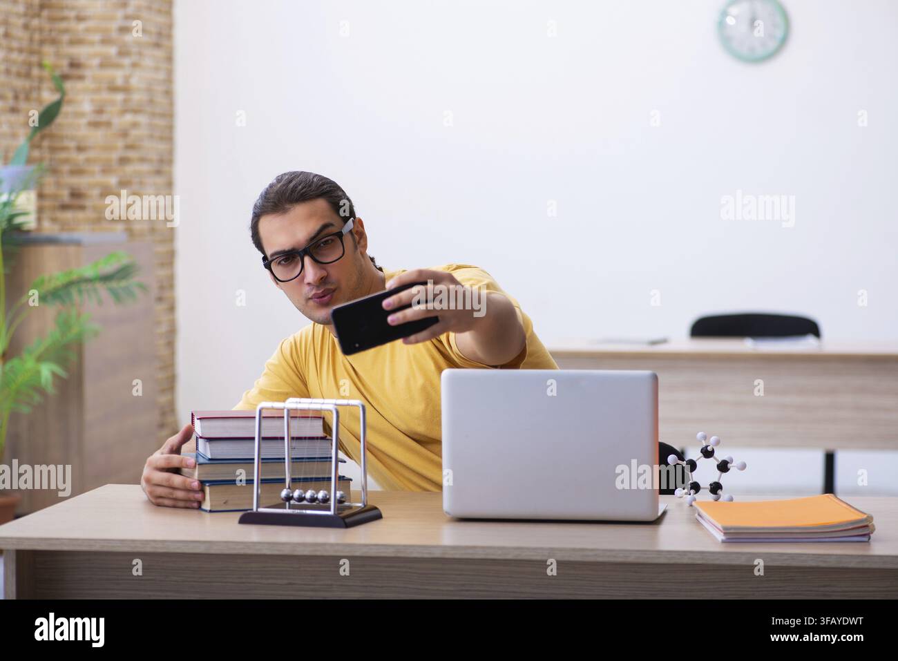 Young student using cell phone while preparing for exams Stock Photo