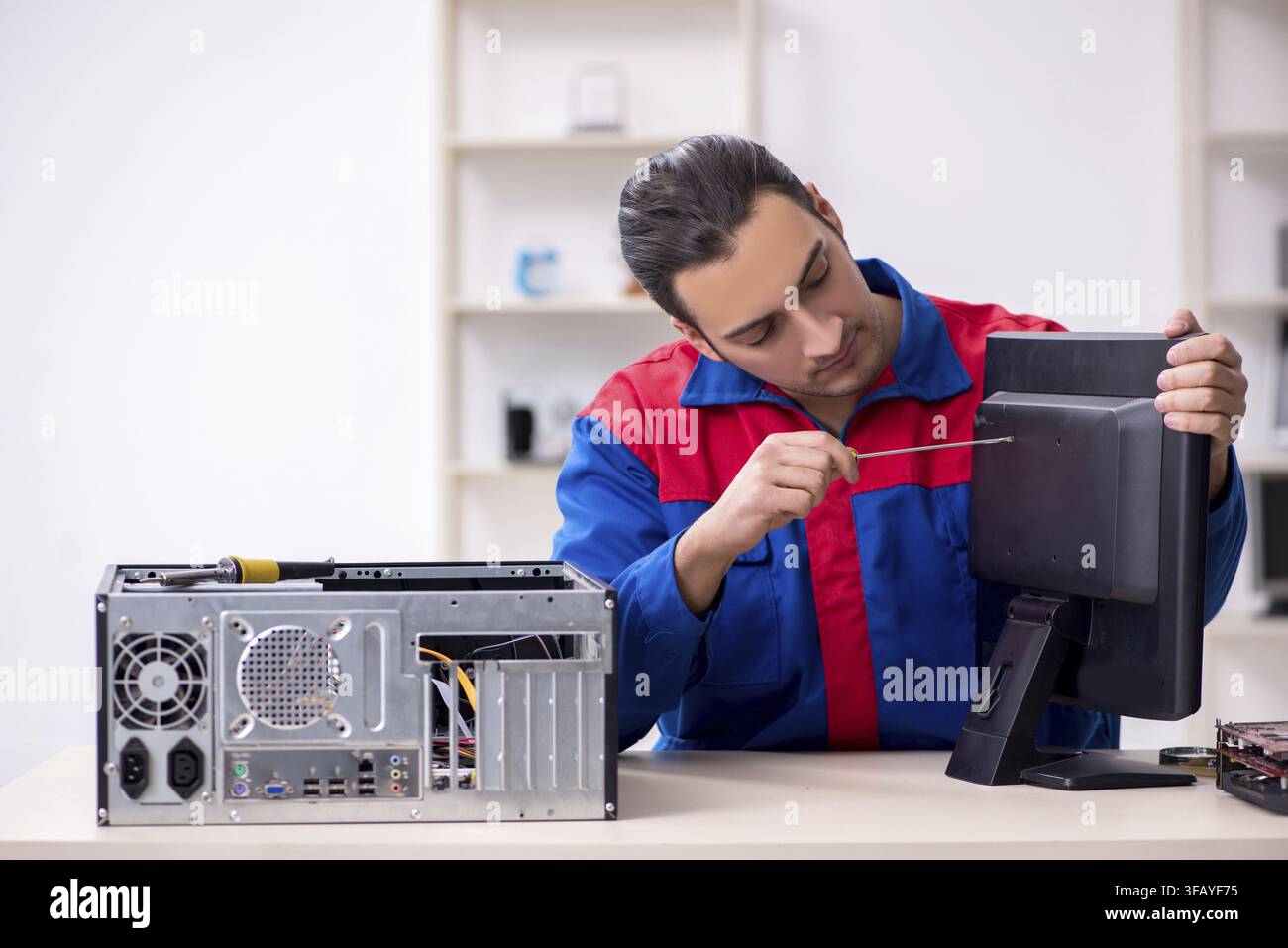 Young male mechanic repairs computer PC Stock Photo
