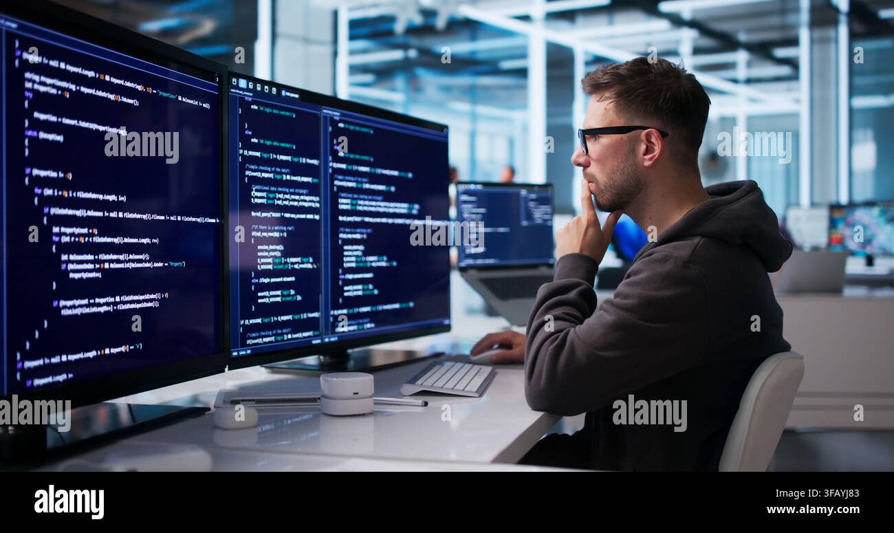 Young Software Engineer Coding Secure Platform At Desktop In Office Workspace. Stock Photo