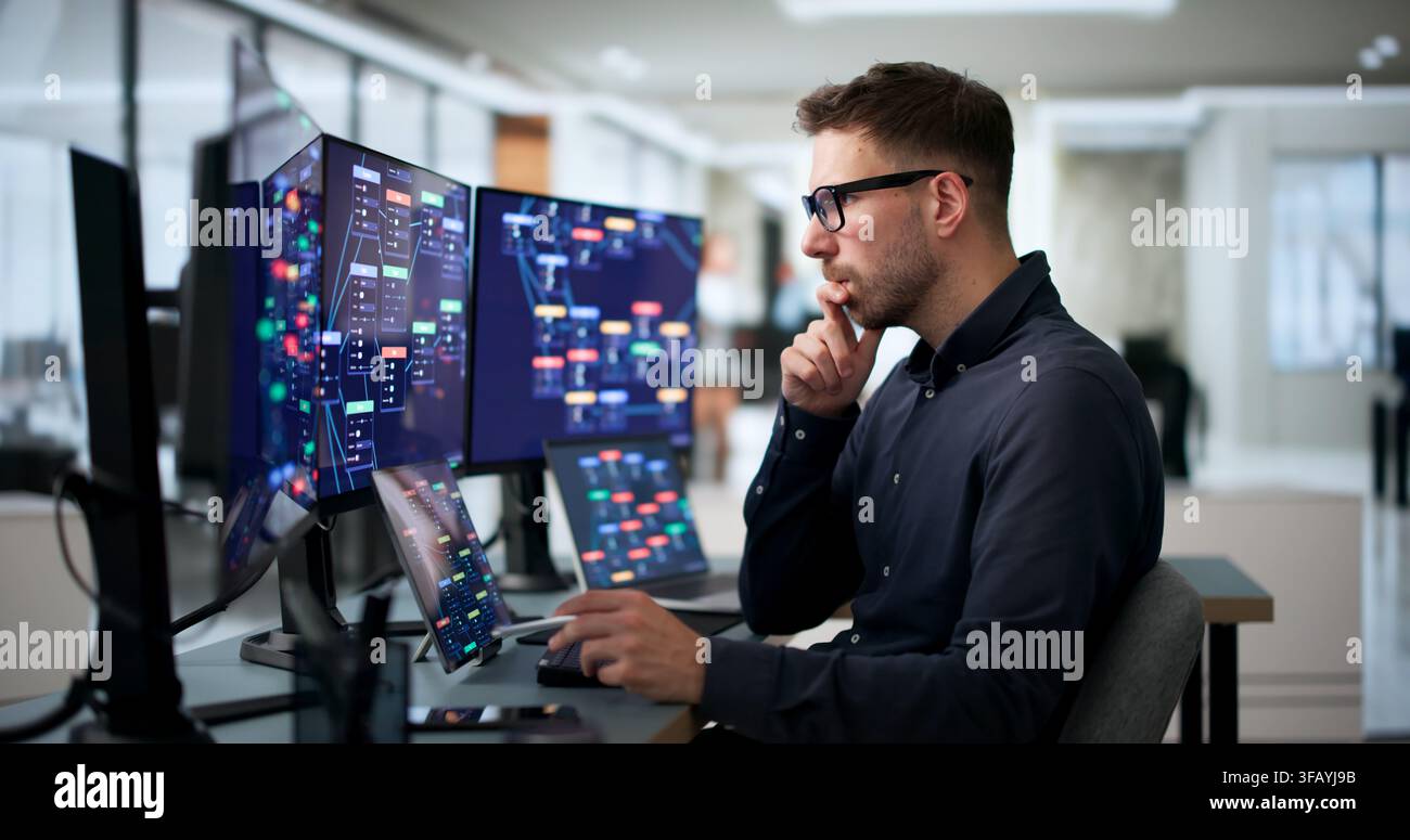 Young Software Developer Uses Laptop And Tablet To Build Workflows Quickly. Stock Photo