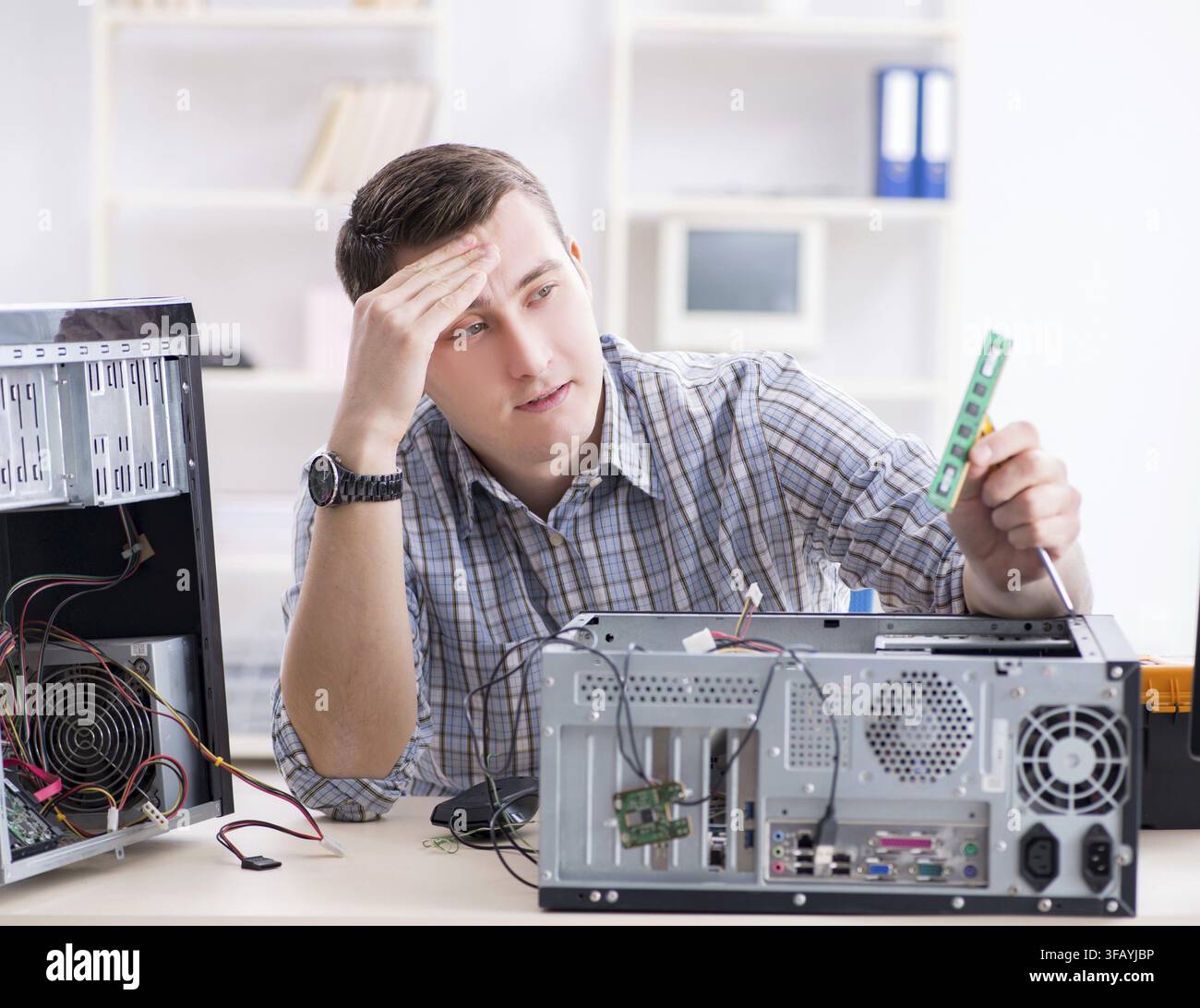 The young technician repairs computers in the workshop Stock Photo