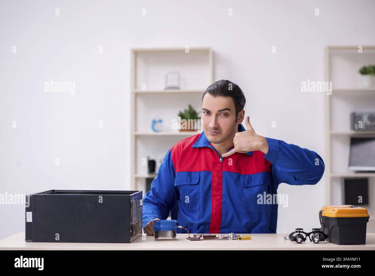 Young male mechanic repairs computer PC Stock Photo