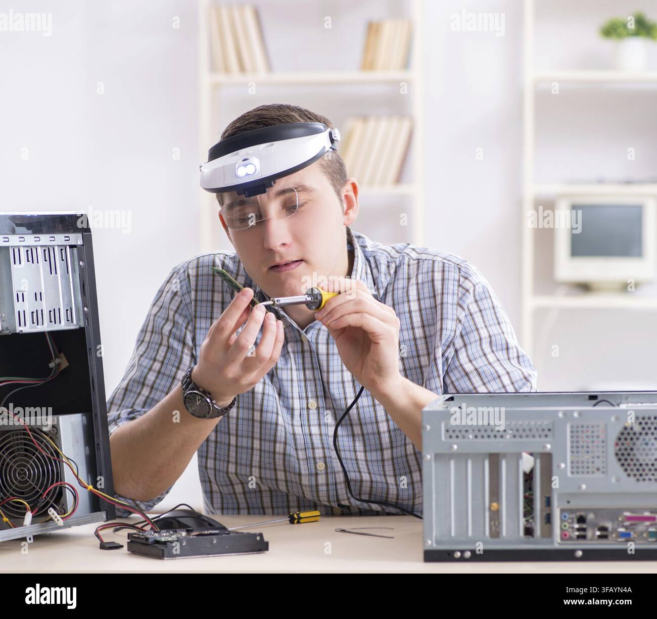 The young technician repairs computers in the workshop Stock Photo