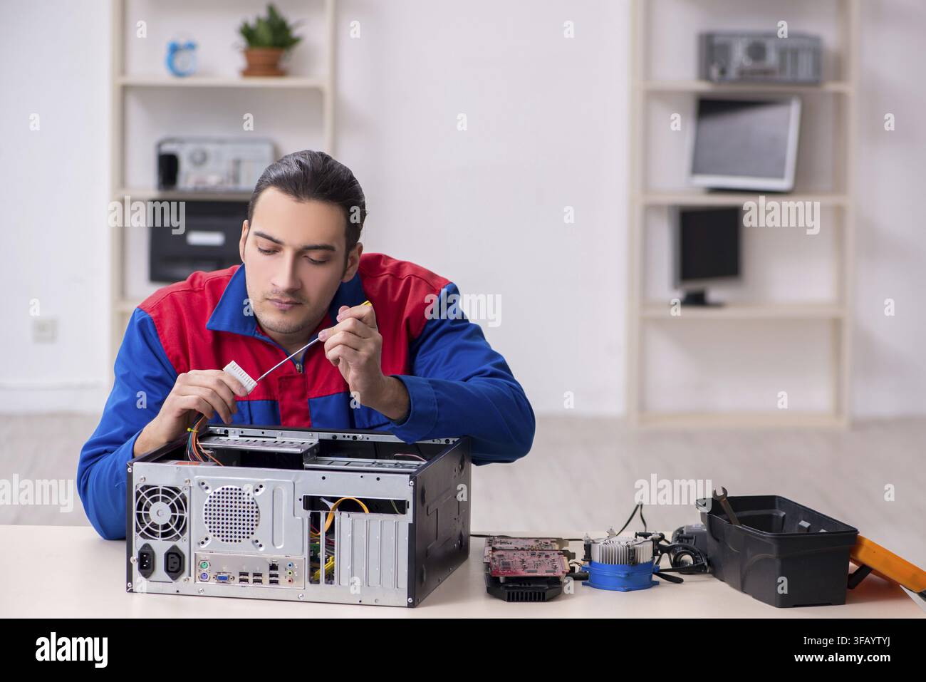 Young male mechanic repairs computer PC Stock Photo