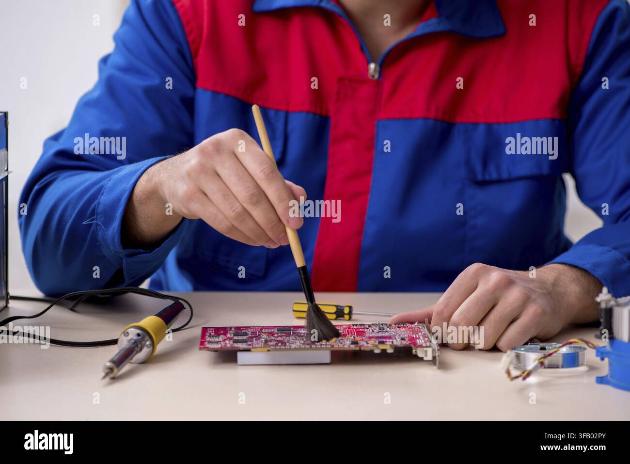 Young male mechanic repairs computer PC Stock Photo