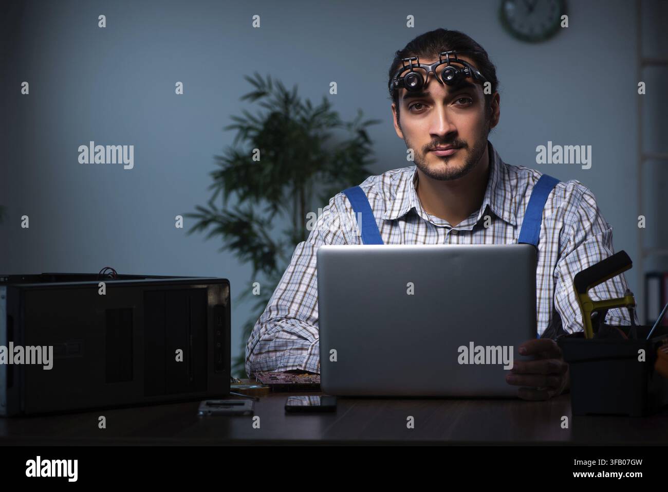 Young technician repairs computers in the workshop at night Stock Photo