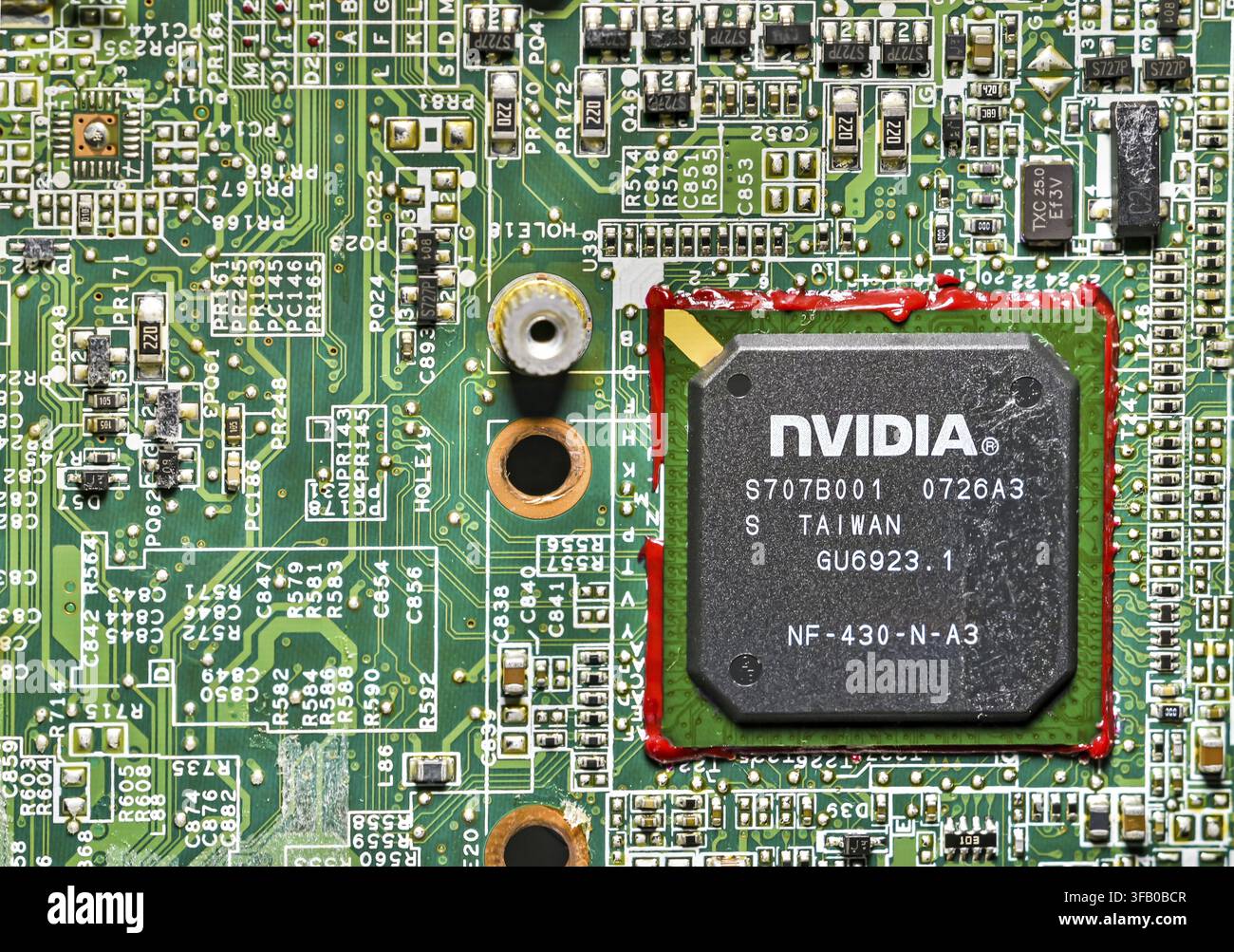 Close-up of an NVIDIA GPU chip mounted on a green laptop motherboard, showing microchips, circuits, and electronic components, representing computer h Stock Photo