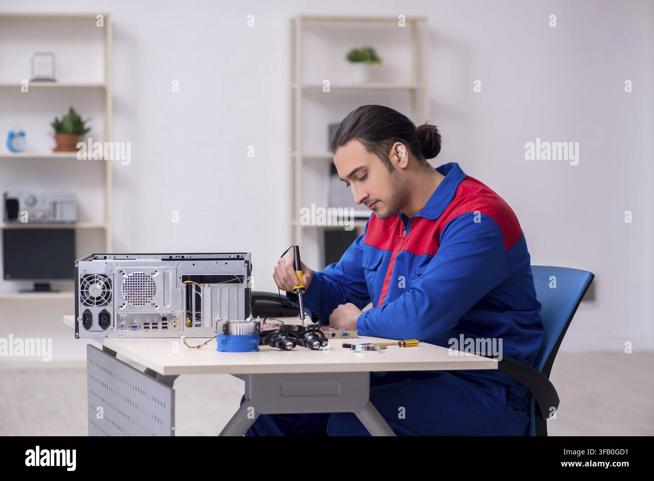 Young male mechanic repairs computer PC Stock Photo