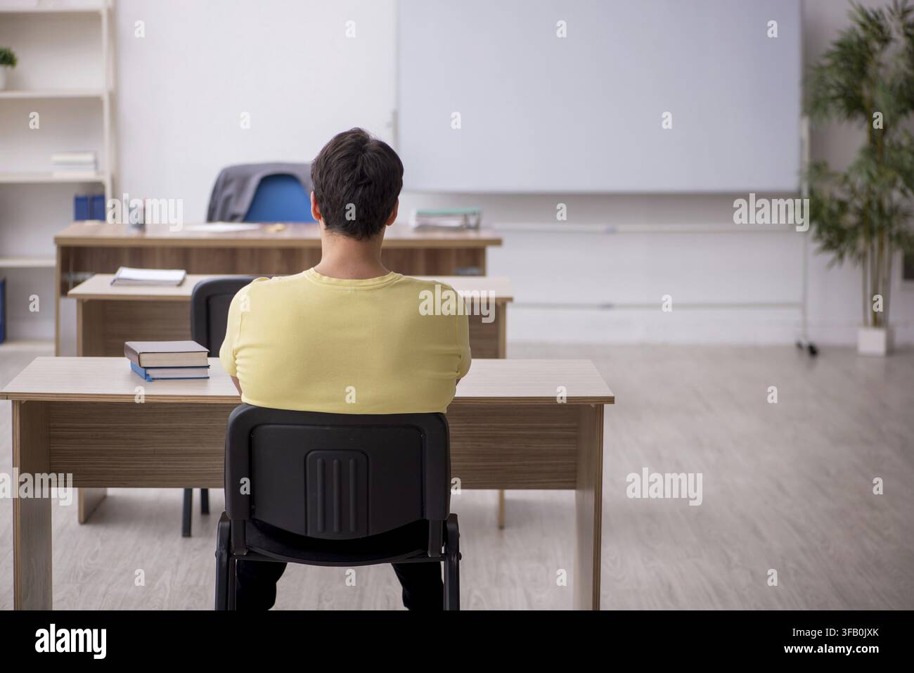 Young student teacher sitting in classroom Stock Photo