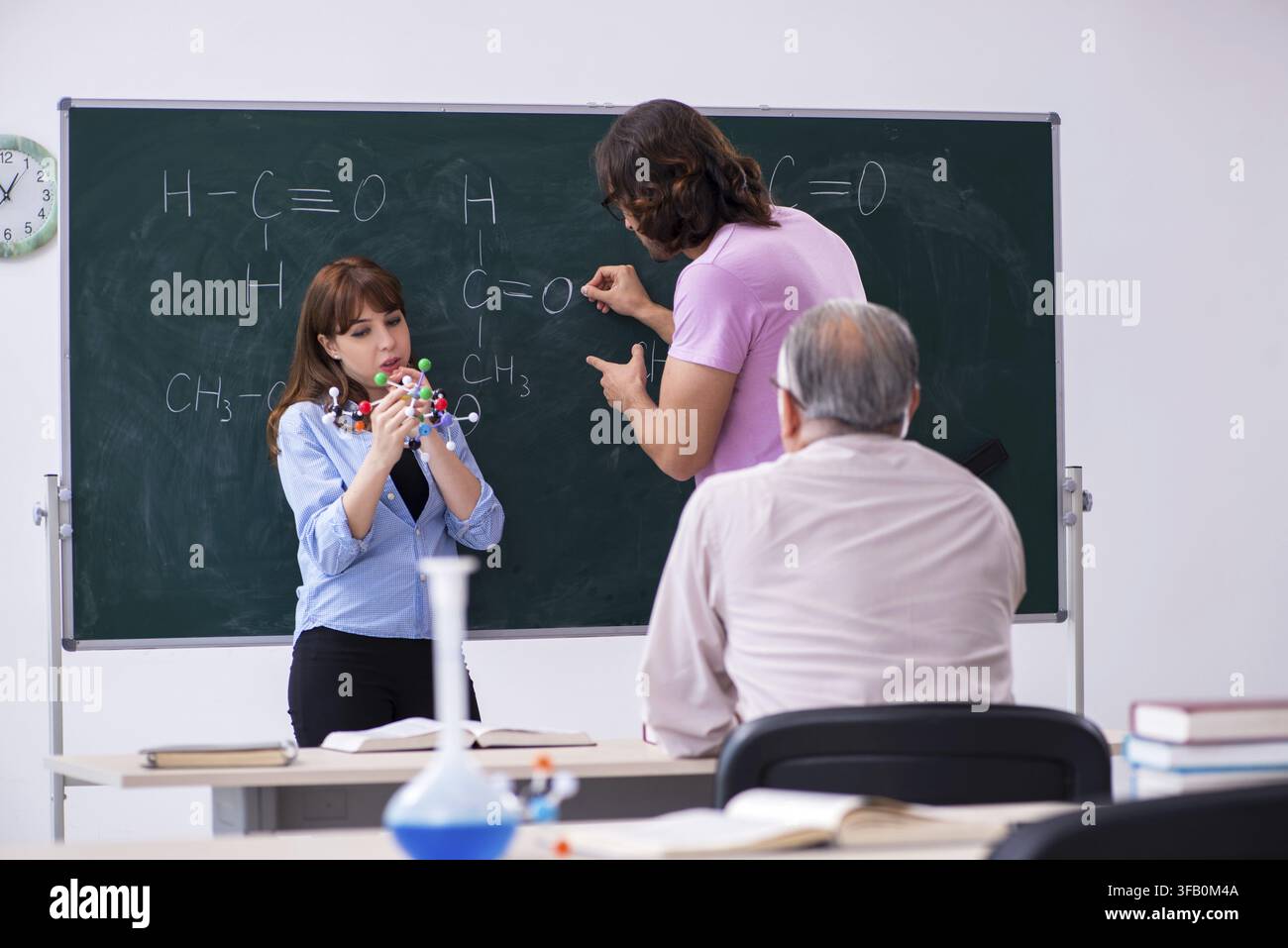 Old teacher and two students in the classroom Stock Photo