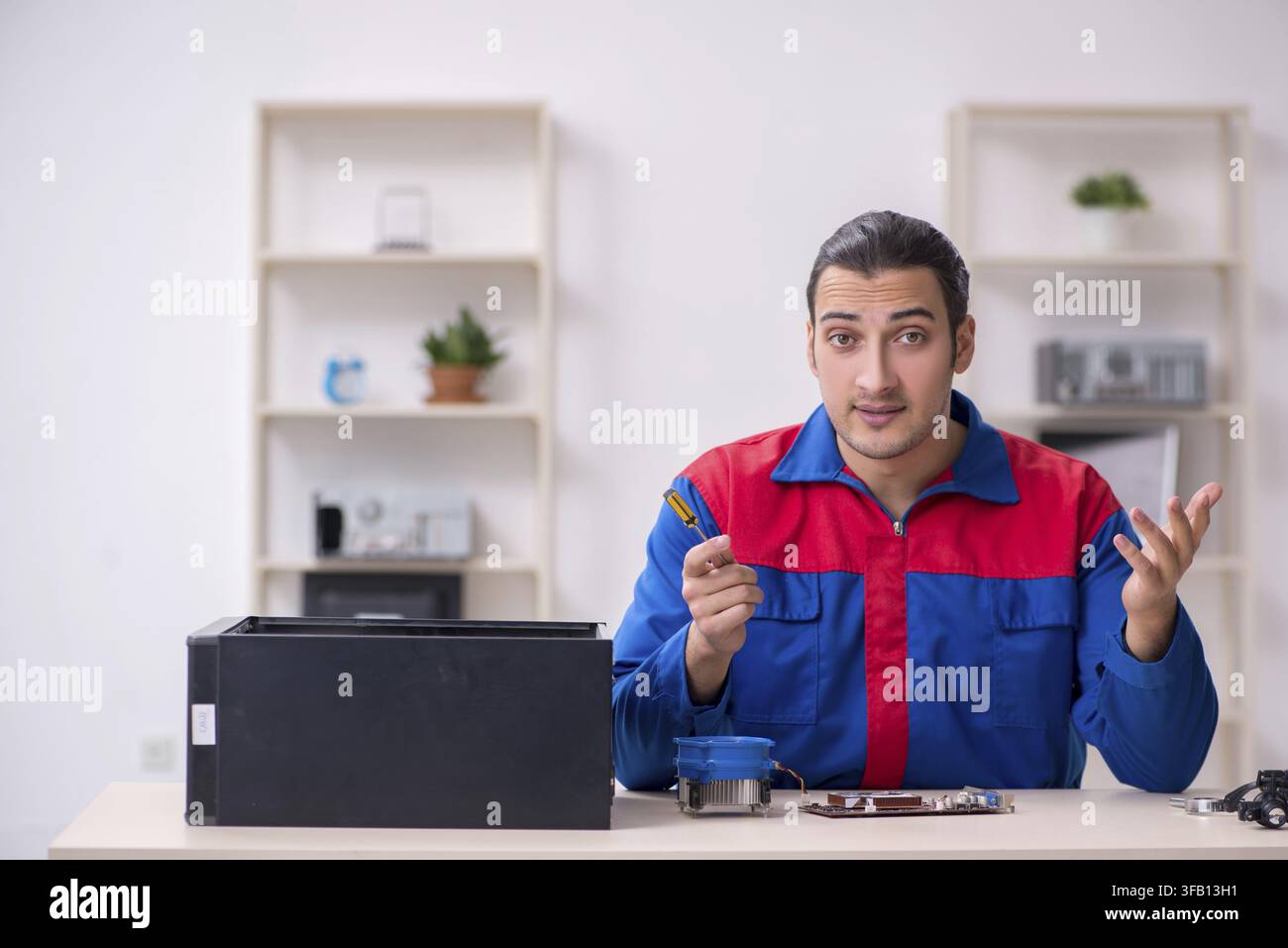 Young male mechanic repairs computer PC Stock Photo