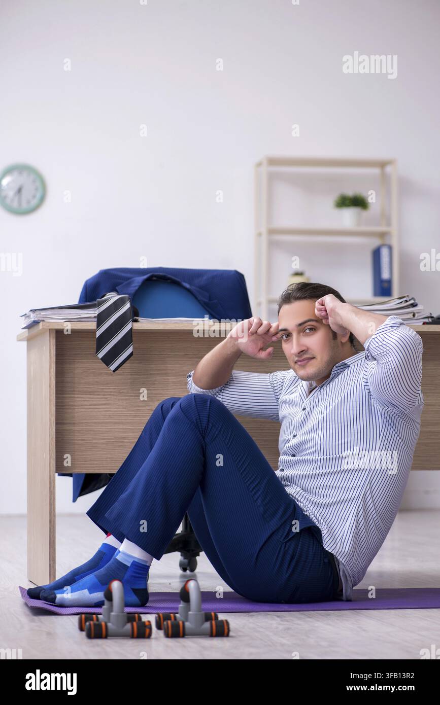 Handsome male employee doing exercises in office Stock Photo